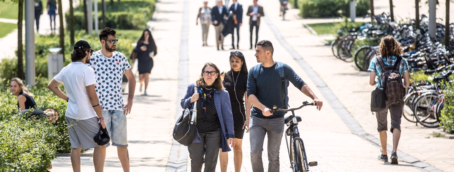 Students walking on campus with a bike