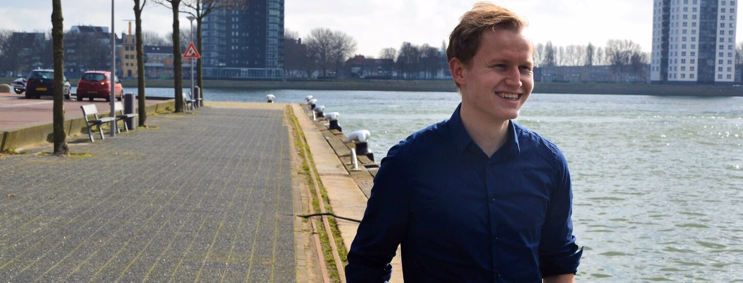 Werner Schouten standing on a dock, laughing, with his hands in his pocket