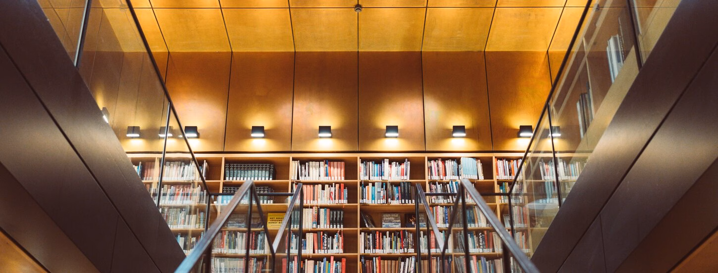 De eerste vedieping van het Rotterdamsch Leeskabinet vanaf de trap gezien, met zicht op de volle boekenkasten