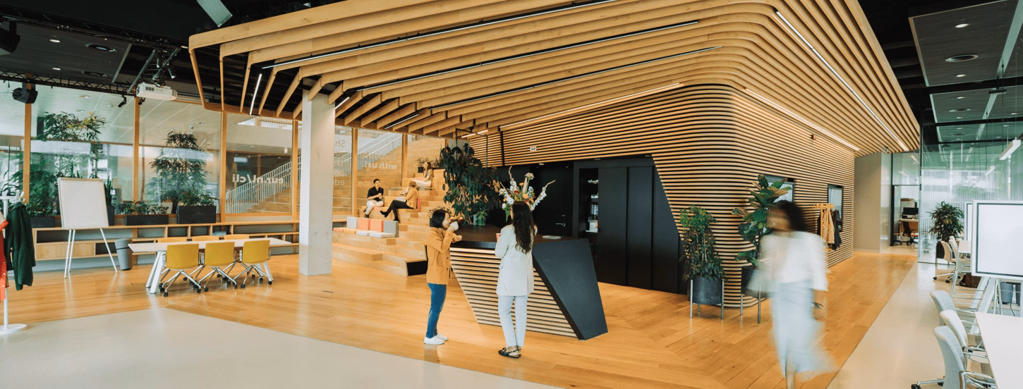 The Erasmus Education Lab, an open space with wood elements. In the space you can see people walking around and talking.