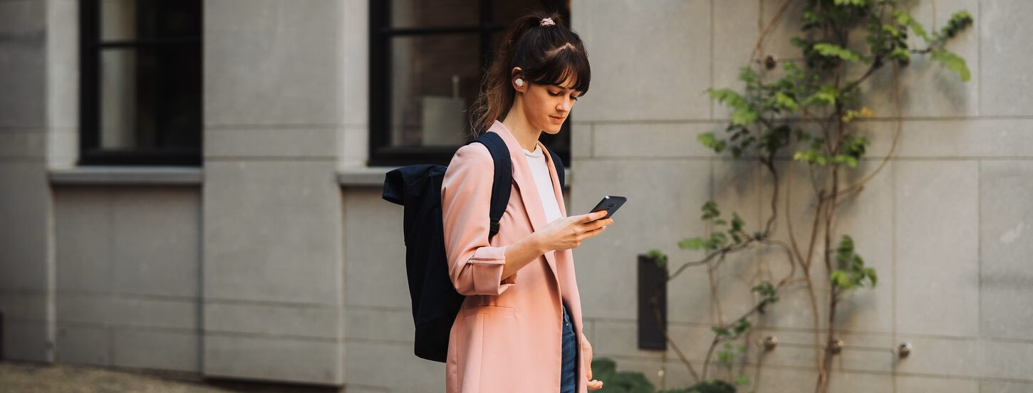 Student loopt kijkend op haar telefoon over straat.