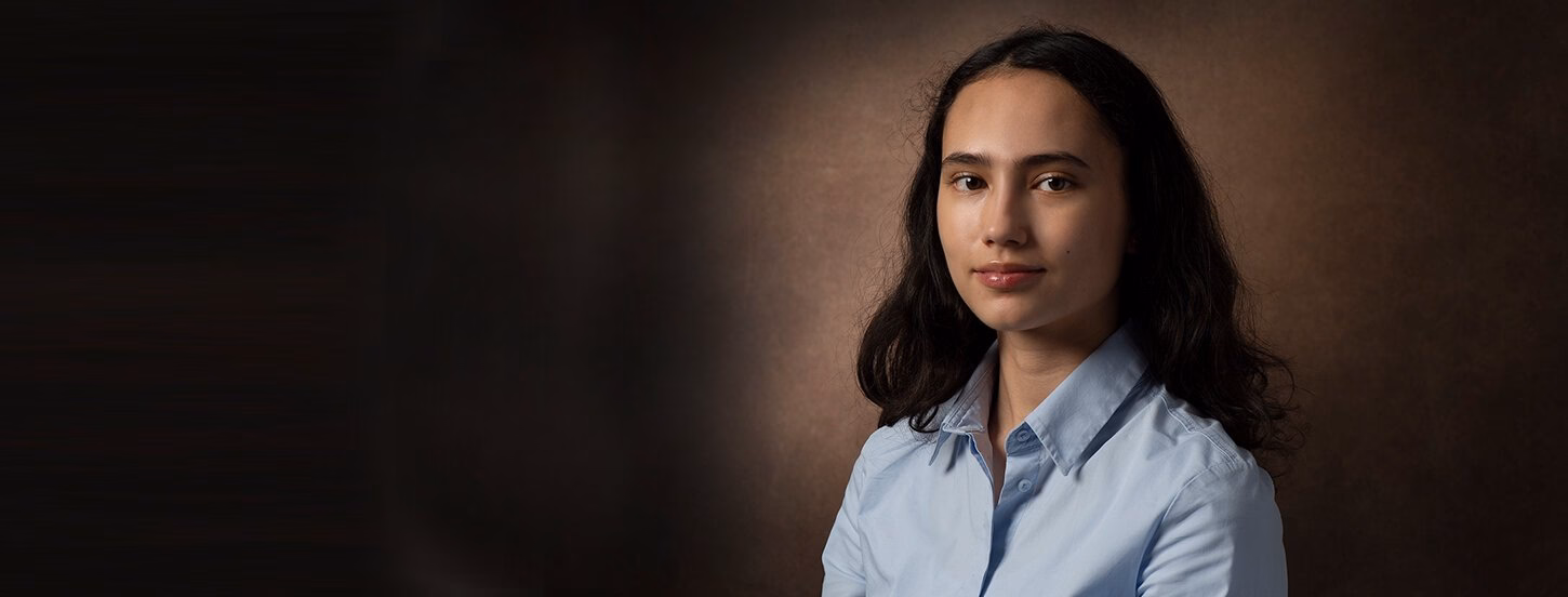 Student smiling with a closed smile at the camera