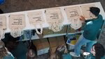 Ambassador stands behind a fabric bag stall during the bachelor open day.