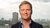 Ronald Huisman smiling with a closed smile with the blurred background of the skyline of Rotterdam