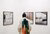 One person with a colourful jacket is standing in front of three artworks with their back towards us.