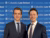 Two smiling men in suits standing before a blue Columbia Law School banner
