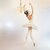 Ballerina dancing in a white gown around a golden chandelier
