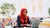Zemzem Shigute Shuka sitting at a table working on her laptop.