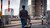 Man walks across Erasmus Bridge with pram.