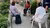 Three Surinamese elderly people sit in a circle on the street chatting to each other.