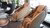 2 beige coloured massage chairs next to a window, a table, some chairs and plants.