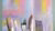 Close-up of the top of brushes with pastel paint on them and a pastel abstract painting in the background