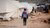 kid with backpack walking through war zone