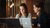 Photograph of two women collaborating on laptops at a wooden table in a warmly lit cafe