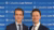 Two smiling men in suits standing before a blue Columbia Law School banner