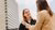Two women in casual jackets chat outside near a tall office building