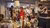 Thrift shop aisle with four shoppers examining lamps and furniture
