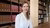 Tabea Krauss, seated at wooden library table with bookshelves behind.
