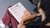 Person with braided hair sitting cross-legged reading a brochure