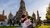 Tourist holds a Think Pink bag in front of Wat Arun temple spires under a blue sky